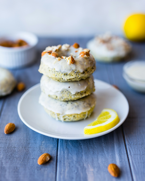 A stack of glazed baked donuts topped with chopped almonds